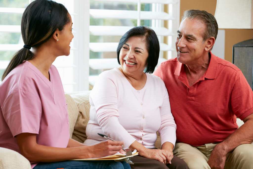 Nurse Making Notes During Home Visit With Senior Couple