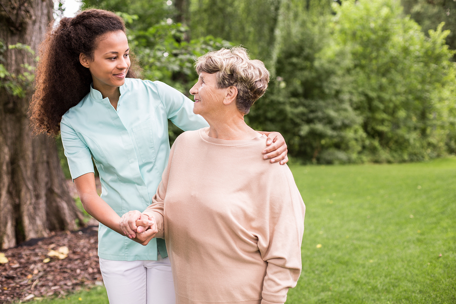 Elder woman and caregiver walking in the park