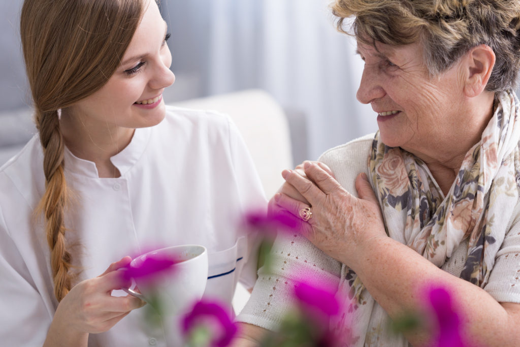 Shot of a young caregiver and her senior patient having a coffee together